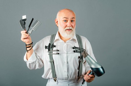 Téléchargez les photos : Barbier senior avec rasoir droit. Coiffeur professionnel senior sur gris isolé - en image libre de droit