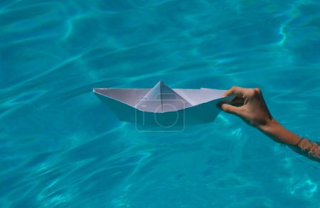 Téléchargez les photos : Paper ship in hand ready to sail. Hand holding paper boat on the sea background - en image libre de droit