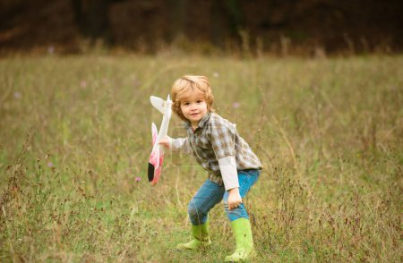 Photo for Child pilot with toy airplane dreams of traveling in summer in nature. Kids dreams. Kid having fun with toy airplane in field. Childhood dream imagination concept - Royalty Free Image