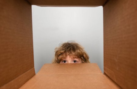 Photo for Child boy looking surprised into a gift. Cheerful cute child opening a present. View from inside of the box. Close up eyes looking - Royalty Free Image