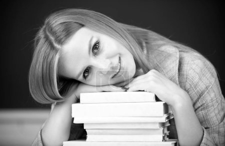 Foto de Primer plano retrato de la joven estudiante atractiva sonriente con libros en el fondo de pizarra con espacio de copia - Imagen libre de derechos