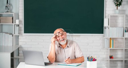 Foto de Retrato de un profesor mayor feliz en el aula. Sonriente viejo profesor o tutor en la universidad. Enseñanza de adultos - Imagen libre de derechos