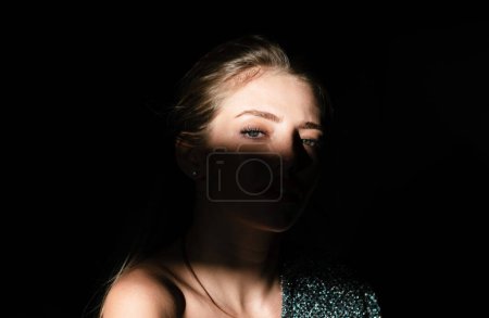 Téléchargez les photos : Elegant young woman posing over black background. Light and shadow. Portrait of a beauty woman face. Passion girl, charming tender female model. Beauty salon - en image libre de droit