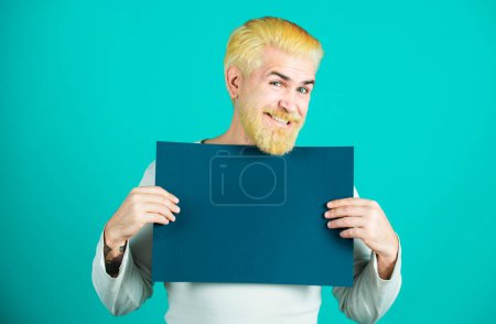 Foto de Retrato del hombre feliz guapo posando y sosteniendo la cartelera azul vacía o el tablero blanco azul - Imagen libre de derechos