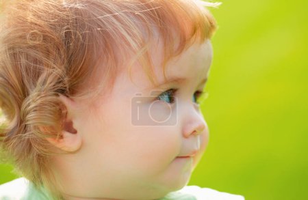 Photo for Cute baby face closeup on green grass in summertime. Funny little kid portrait on nature. Happy Childhood - Royalty Free Image