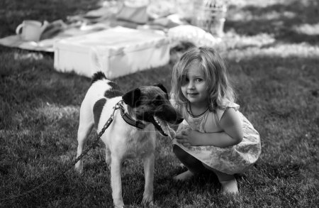 Photo for Little baby playing girl with Russell Terrier dog in nature on the green grass. Kids playing. Baby and summer sunny weather - Royalty Free Image