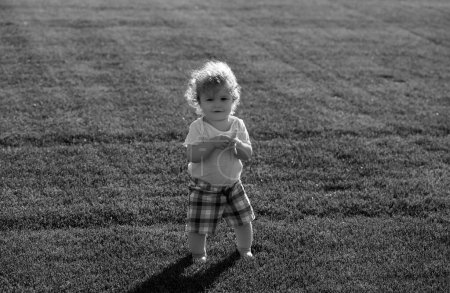 Foto de Bebé en el hermoso campo verde de primavera. Niño sano - Imagen libre de derechos