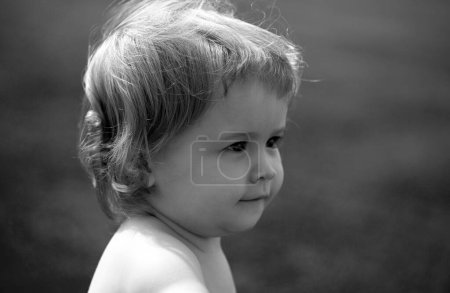 Foto de Retrato de un niño jugando al aire libre en la hierba. Cara de bebé de cerca. Gracioso retrato de primer plano de niño. Niño rubio, cara de emoción - Imagen libre de derechos