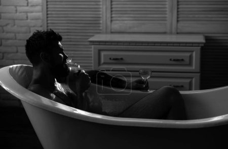 Téléchargez les photos : Homme barbu buvant et fumant dans le bain. Dépression masculine. Émotions négatives - en image libre de droit