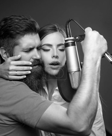 Téléchargez les photos : Un chanteur et une chanteuse dans un studio. Couple sensuel avec microphone. Signataire karaoké, chanteur musical - en image libre de droit