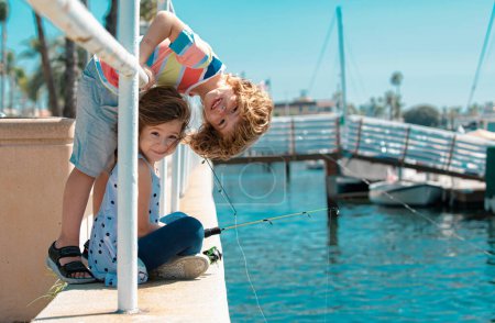 Foto de Kids fishing. Couple of children fishing on pier. Children at jetty with rod. Boy and girl with fish-rod - Imagen libre de derechos