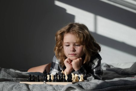 Photo for Cute boy are playing chess at home. Clever concentrated and thinking kid playing chess. Kids brain development and logic game - Royalty Free Image