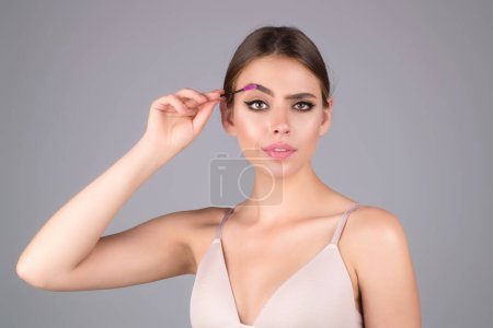 Téléchargez les photos : Woman shaping brown eyebrows. Woman eye with beautiful eyebrows. Shaped brows, long eyelashes. Paint eyebrows. Girl contouring eyebrows on isolated studio background - en image libre de droit