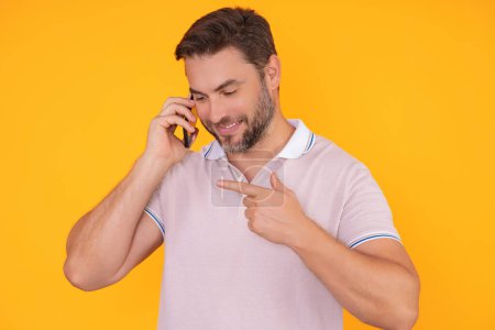 Handsome man in t-shirt using mobile phone isolated on studio background. Portrait of confidence middle aged millennial hispanic man using cellphone. Guy with smartphone isolated studio background