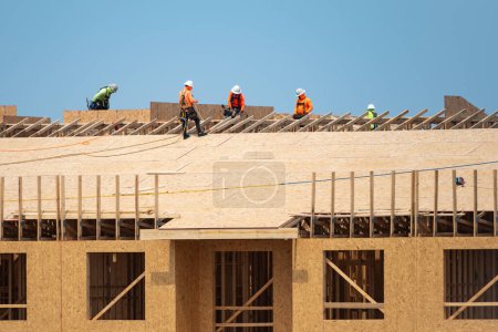 Foto de Carpintero tejado trabajando en la estructura del techo en el sitio de construcción. Roofer en el trabajo de techado. Techo en el lugar de trabajo alto. Trabajadores en obras de construcción de techos. Trabajo de tejado. Herramientas para techos de madera - Imagen libre de derechos