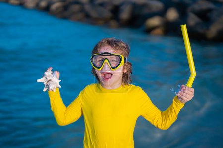 Foto de Emocionantes vacaciones de verano. Un chico divertido usando una máscara de buceo de snorkel encontró un coral o concha en el agua del océano. Summer Kids Buceo de snorkel. Emocionado niño se sumerge en el agua. Vacaciones de verano - Imagen libre de derechos