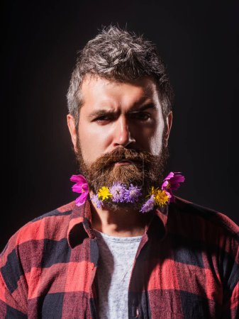 Foto de Un hombre barbudo con barba decorada para las vacaciones de primavera. Flor en la barba. Champú y acondicionador para una barba limpia y suave. Cuidado de belleza del hombre, cuidado del vello facial. Aceite de barba - Imagen libre de derechos