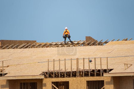Photo for Roofing on roof. Builder roofer install new roof. Construction worker roofing on a large roof apartment building development. Roofer carpenter working on roof structure construction site - Royalty Free Image