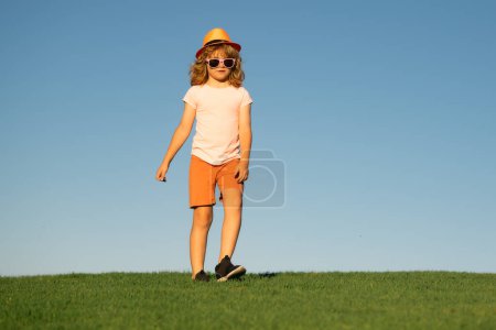 Foto de Chico deportivo corriendo en la naturaleza. Niño sano activo correr al aire libre. Niño divirtiéndose y corriendo sobre hierba verde cerca del cielo azul en el parque - Imagen libre de derechos