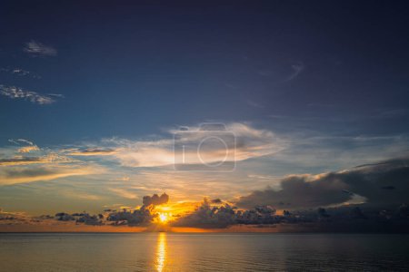 Foto de Puesta de sol en la playa tropical mar océano con nubes del amanecer. Banner para vacaciones de viaje. Paisaje cielo y reflejos rayos en el agua. Salida del sol en la playa sobre el mar tropical. Tranquilo, fondo dorado del cielo - Imagen libre de derechos