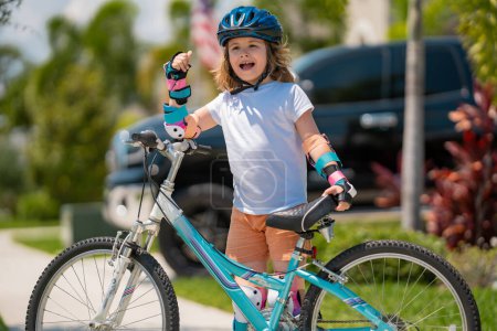 Photo for Cute kid riding a bike in summer park. Children learning to drive a bicycle on a driveway outside. Kid riding bikes in the city wearing helmets as protective gear. Child on bicycle, bike outdoor - Royalty Free Image
