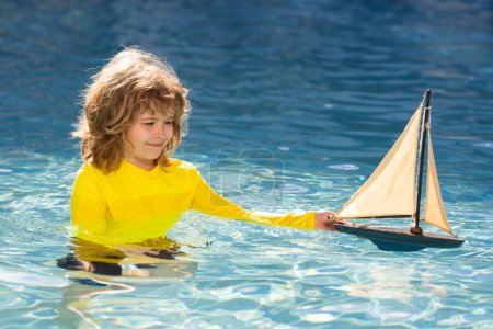 Photo for Summer kids portrait. Child with toy boat in sea water on summer vacation. Child playing with toy seailing boat on sea. Summer vacation, child playing with toy boat at beach. Child with toy ship - Royalty Free Image