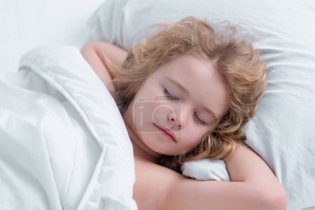Foto de Hermosa cara de niño rubia caucásica, durmiendo en la cama. Dulces sueños. Pequeño niño durmiendo tumbado en la cama en casa - Imagen libre de derechos