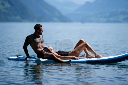 Téléchargez les photos : Couple sexy se reposer en planche à pagaie. Couple pagayant sur la planche à pagaie. Amoureux hispaniques sur planche à sup paddle surf. Surf SUP en vacances d'été dans les Alpes lac en Suisse - en image libre de droit