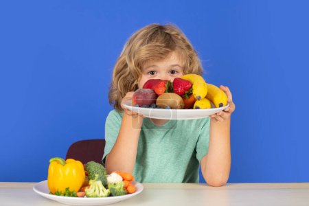 Téléchargez les photos : Fruits et légumes pour enfants. Enfants en bonne santé tiennent assiette avec des fruits - en image libre de droit
