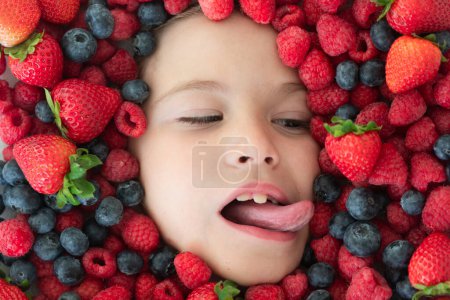 Téléchargez les photos : Vitamines de berrie. Berries enfant visage de près. Photo du visage de l'enfant avec Berri. Berry près du visage des enfants. Mignon petit garçon mange des baies. Il mange des vitamines. Gros plan enfants visage - en image libre de droit