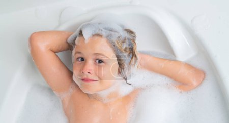Kind, das Spaß im Bad mit Blasen hat. Glückliches Kind, das die Badezeit genießt. Kleiner Junge lächelt in der Badewanne mit Seifenschaum. Badewanne mit Seifenblase. Kind badet in Badewanne mit Schaum
