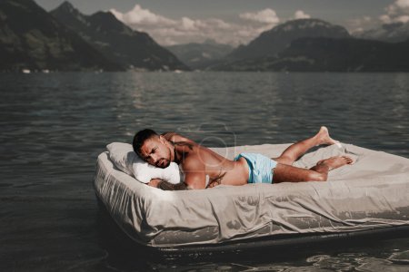 Photo for Summer Travel vacation holiday. Relax man, freedom, calm and carefree on summer concept. Muscular man lying on cozy Mattresses, sleep, good dreams concept. Sexy man floating on the Bed with blanket - Royalty Free Image