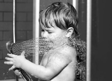 Téléchargez les photos : Le gamin s'amuse à se baigner. Bains de bébé heureux drôles dans la baignoire avec de l'eau et de la mousse. Hygiène des enfants - en image libre de droit