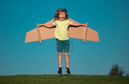 Photo for Child boy plays pilot astronaut. Kid dreaming of becoming a aviator spaceman. Child on a blue sky background playing with a cardboard wings plane - Royalty Free Image