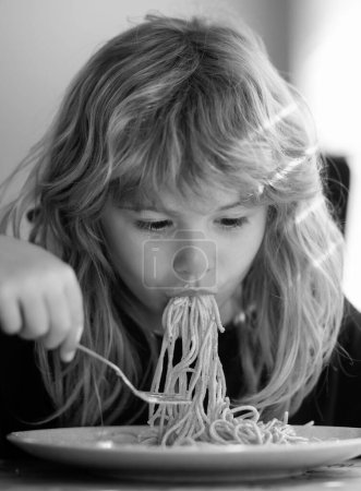 Tasty food, messy child eating spaghetti. Child have a breakfast. Tasty kids breakfast. Childcare and childhood. Close up portrait of funny kid eating noodles pasta