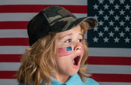 Téléchargez les photos : Kid célébration indépendance jour 4 juillet. Concept des États-Unis d'Amérique. Enfant avec drapeau américain. Jour du Souvenir. Visage drôle d'enfants avec drapeau américain sur la joue. Visage surprenant des enfants - en image libre de droit