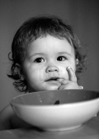 Téléchargez les photos : Bébé heureux se mangeant avec une cuillère. Lécher les doigts savoureux - en image libre de droit