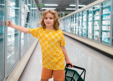 Photo for Child with shopping basket at grocery store. Healthy food for kids. Portrait of smiling little child with shopping bag at grocery store or supermarket - Royalty Free Image