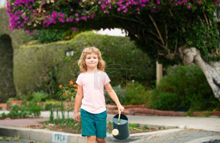 Foto de Niño en el jardín. Retrato de un niño que trabaja con regadera en el jardín en vacaciones - Imagen libre de derechos