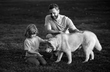 Photo for Childhood and parenthood kids concept. Happy father and son playing with pet dog outdoor. Child with her pet friend - Royalty Free Image