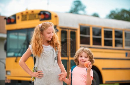 Téléchargez les photos : Je retourne à l'école. Photo de deux enfants heureux regardant par les fenêtres d'un autobus scolaire jaune. Beaucoup d'espace pour le texte - en image libre de droit