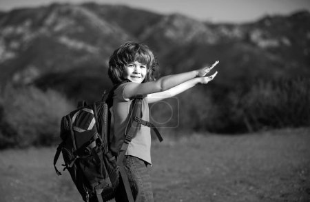 little boy with backpack hiking in scenic mountains. Kid local tourist goes on a local hike