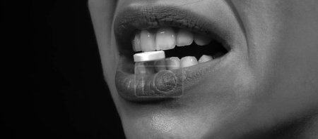 Nahaufnahme der Pille in Frauenzähnen. Lippen halten Tabletten im Mund. Nahaufnahme einer kranken Frau, die Pille gegen Schmerzen, tägliche Nahrungsergänzungsmittel oder Antidepressiva in den Mund nimmt