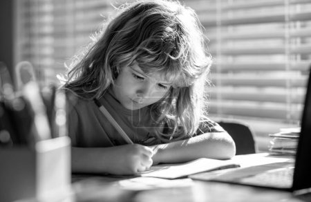 Photo for Child writing at school. Portrait of school kid boy siting on table doing homework. Child holding pencil and writing. Boy drawing on white paper at the table - Royalty Free Image