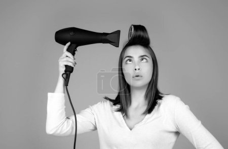 Woman with hair dryer. Funny girl with straight hair drying hair with professional hairdryer. Hairstyle, hairdressing concept