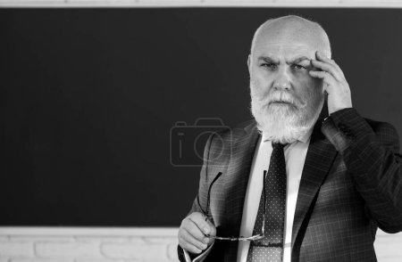 Foto de Profesor de pensamiento masculino mayor de pie frente a una pizarra en un aula. Piensa en senior. Concepto de trabajo y aprendizaje del profesorado - Imagen libre de derechos