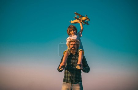 Foto de Padre e hijo jugando con un avión de madera. Padre cargando a su hijo en hombros - Imagen libre de derechos