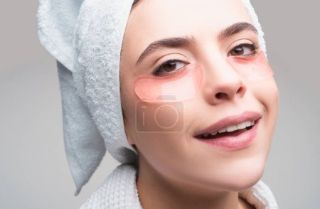 Photo for Close up portrait girl with towel on head. Portrait of beauty woman with eye patches showing an effect of perfect skin. Brunette spa girl. Eyes mask cosmetic patches woman face closeup - Royalty Free Image