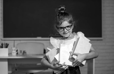 Photo for Portrait of funny pupil girl of primary school holds books. Elementary school and primary education - Royalty Free Image