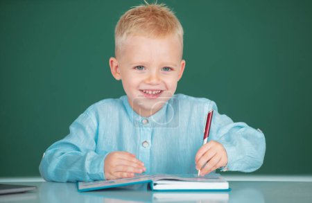 Photo for School boy studying math on lesson in classroom at elementary school. Happy pupil near chalkboard during lesson at primary school, close up portrait - Royalty Free Image